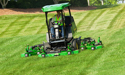 Green John Deere Tractor cutting green grass